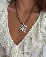 Collar con tiento marrón y dije de acero quirúrgico en forma de flor.