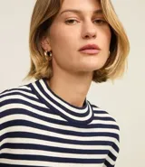 Sweater de punto de manga larga, con rayas horizontales en azul marino y blanco. Presenta cuello redondo ligeramente elevado y puños y ruedo en color blanco liso.