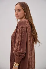 Sweater de punto color marrón chocolate, con diseño de trenzas y rombos en el frente, cuello redondo y mangas largas con puños acanalados.
