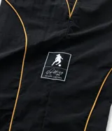 Pantalón deportivo de microfibra color negro, con corte holgado y diseño de piping contrastante en color amarillo. Cuenta con cintura elástica con cordón de ajuste, bolsillos laterales y logo bordado.
