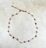 Collar delicado de cadena dorada con pequeñas piedras naturales en tonos variados, dispuestas de forma sutil a lo largo de la pieza.