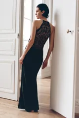 Vestido largo de satén con cuello halter ajustable y hombros descubiertos. Presenta un diseño elegante con espalda detallada en tejido con relieve y bordados perforados. Incluye cierre lateral con cremallera oculta.