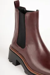 Bota marrón de cuero sintético, estilo Chelsea, con punta redonda, pieza elastizada en los laterales y suela tipo tractor de 6cm de alto.