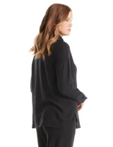 Buzo de tejido suave color gris melange, con cuello volcado ajustable mediante cordones con punteras metálicas. Presenta mangas largas con puños anchos decorados con botones metálicos, hombros caídos y un diseño de silueta holgada con ruedo redondeado y aberturas laterales.