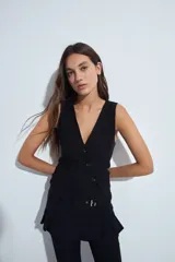 Top tipo chaleco de estilo sastrero, color negro, con escote en V profundo y cierre frontal mediante botones. Presenta un corte entallado y diseño sin mangas.