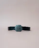 Cinturón de cuero negro con hebilla metálica hexagonal de diseño floral grabado y centro con relieve.