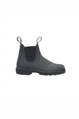 Botas tipo chelsea Blundstone modelo 587, confeccionadas en gamuza repelente al agua de color gris oscuro. Presentan paneles elásticos laterales negros, tiradores en la parte superior y suela de TPU antideslizante con entresuela acolchada para mayor absorción de impactos.