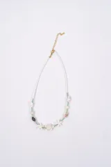 Collar de estilo playero compuesto por pequeñas cuentas blancas, intercaladas con cuentas turquesas y doradas. Presenta dijes de caracoles, estrellas de mar y una tortuga marina en el centro.