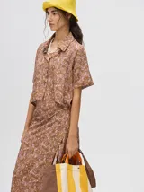 Camisa corta celeste con estampado de nubes, cuello clásico, manga corta y cierre frontal con botones.