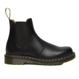 Bota Chelsea Dr. Martens modelo 2976, confeccionada en cuero liso negro con inserciones elásticas laterales, tirador en el talón y suela con cámara de aire reforzada con pespunte amarillo característico.