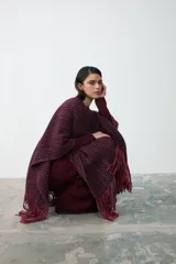 Ruana artesanal tejida en lana, con diseño de trama multicolor en tonos bordó, violeta y naranja, terminada con flecos en los extremos.