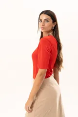 Remera de cuello redondo y manga corta, confeccionada en tejido elástico con un acabado suave y un leve brillo. Presenta un diseño básico con un pequeño isotipo bordado en la espalda.