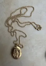 Collar dorado con cadena de bolitas y dije ovalado con la imagen de la Virgen Milagrosa.