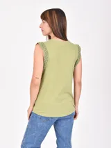 Remera blanca sin mangas con detalle de encaje en los hombros, cuello redondo y corte recto.