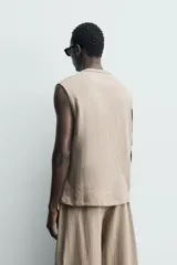 Sudadera sin mangas de corte relajado, confeccionada en tejido con textura irregular y acabado interior tipo rizo. Presenta cuello redondo y diseño de sisa amplia.