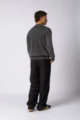 Sweater de tejido de punto grueso color tostado, con cuello redondo y mangas largas con puño elástico que incluye una etiqueta decorativa.