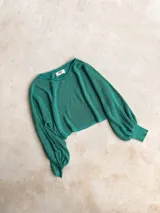 Buzo de tejido de punto color verde con destellos dorados, de corte holgado, cuello redondo y mangas largas abullonadas con puños ajustados.