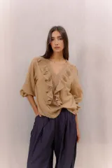Camisa blanca de algodón con escote en V, volados delanteros con detalles de encaje y mangas largas con puños fruncidos.