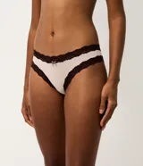 Kit de dos bombachas tipo bikini confeccionadas en microfibra, con detalles de encaje contrastante en los bordes y un pequeño lazo decorativo en el centro. Una pieza es de color beige y la otra de color marrón oscuro.