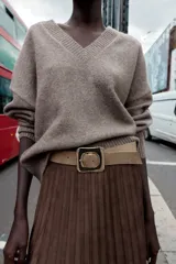 Falda midi plisada de tiro alto color marrón, con cinturón ancho de color beige y hebilla metálica cuadrada. Cierre lateral con cremallera oculta.