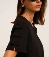 Blusa negra de crepé con cuello redondo y mangas cortas decoradas con lazos aplicados.