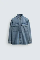 Sobrecamisa de denim de algodón con efecto lavado, corte regular fit, cuello solapa, cierre frontal de botones, manga larga con puños abotonados y dos bolsillos frontales con solapa en el pecho.