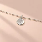 Pulsera de plata 925 con cadena de eslabones y pequeñas cuentas esféricas intercaladas, con un dije colgante en forma de medalla circular grabada con la figura de una abeja.