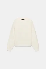 Jersey de punto color marfil, con cuello redondo y diseño de manga larga con hombros caída.