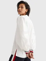 Blusa de manga larga Tommy Hilfiger confeccionada en algodón orgánico. Presenta un cuello en V amplio y puños elásticos con el diseño de rayas distintivo de la marca en colores blanco, rojo y azul marino.