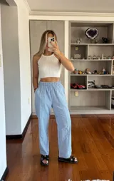 Pantalón de tiro alto con estampado de rayas verticales en azul y blanco. Presenta cintura elástica fruncida, bolsillos laterales y un corte de pierna recta y holgada.