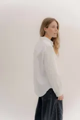 Camisa de manga larga color rosa claro con textura, cuello y puños blancos contrastantes. Los puños tienen tres botones rosados.