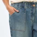 Jeans mom de color azul claro, con cintura elástica fruncida, bolsillos delanteros tipo cargo y puños elásticos en los tobillos.