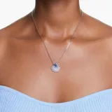 Colgante con cadena plateada y dije en forma de concha de mar con cristal central azul y circonitas blancas.