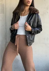 Campera negra de cuero sintético, con cuello de piel sintética con estampado animal print, cierre frontal con botones a presión, bolsillos con solapa en el pecho y corte recto.