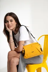 Bandolera amarilla de lona con correa ajustable, bolsillos laterales y bolsillo frontal.