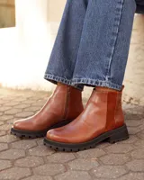 Botas tipo chelsea de cuero color marrón óxido, con paneles laterales de textura combinada y suela track negra de goma.