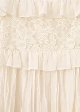 Vestido corto color crudo, con tirantes finos, detalles de encaje y volados en el pecho.