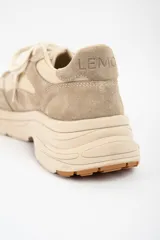 Zapatilla urbana de diseño chunky, confeccionada en una combinación de cuero liso y gamuza en tonos beige y arena. Presenta cordones al tono, suela de plataforma con relieve y detalle de marca grabado en el talón.