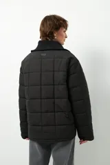 Campera marrón capitoneada de manga larga con cuello alto de tela, cierre frontal y bolsillos laterales con cierre.