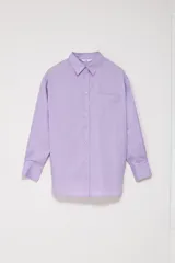 Camisa oversize color lavanda de poplin con cuello clásico, cierre frontal con botones, manga larga con puños abotonados y bolsillo de parche en el pecho.
