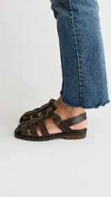 Sandalias de cuero color marrón, estilo romano con tiras entrelazadas, punta cuadrada y cierre de hebilla metálica en el tobillo.