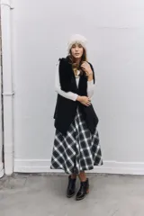 Chaleco negro con interior y bordes de piel sintética, diseño abierto sin cierre.