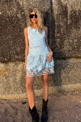 Vestido corto celeste de encaje bordado, sin mangas y con volados en la falda. Incluye un top y una calza tipo biker que se usan por debajo.