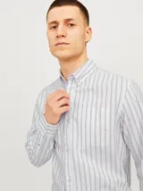 Camisa de manga larga Jack & Jones, confeccionada en tejido Oxford de algodón 100%. Diseño a rayas verticales en tonos beige y blanco, con cuello abotonado, bolsillo en el pecho y corte regular.