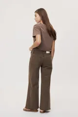 Pantalón jean de tiro medio, color negro, de corte amplio y silueta extra wide leg. Presenta diseño clásico de cinco bolsillos, cierre frontal con botón y cremallera, y detalle de tachas metálicas aplicadas a lo largo de los laterales.