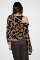Chaqueta de punto con textura suave, cuello redondo y manga larga. Presenta un diseño de estampado animal print en tonos marrones y negros, con cierre frontal de botones.