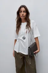 Remera de manga corta color blanco con cuello redondo y detalle de frunce lateral que aporta movimiento y una silueta entallada.