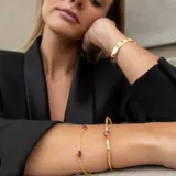 Brazalete ajustable de plata 925 bañada en oro 18k con una piedra granate central en forma de gota.