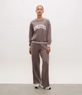 Buzo deportivo de corte oversized color gris topo, con cuello redondo, mangas largas y puños con detalle de rayas blancas. Presenta estampado frontal con la palabra Athletics y ruedo con franja blanca contrastante.