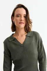 Vestido corto de tejido de punto color verde oliva, con cuello polo, escote en V y mangas largas. Presenta un diseño ajustado con textura acanalada.
